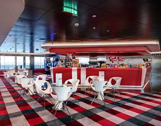 A spacious and modern sports bar with sleek furnishings and large windows offering scenic views | MSC Cruises