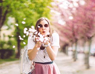 A woman in sunglasses enjoys a sunny day, surrounded by blossoming trees while holding a camera | MSC Cruises