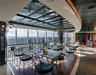 Stylish restaurant featuring large windows that offer a stunning view and inviting atmosphere | MSC Cruises