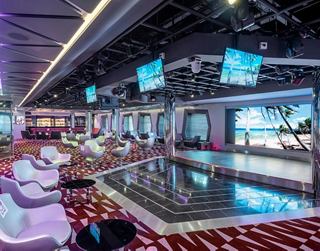 A stylish TV studio bar featuring modern seating and screens, creating a vibrant social atmosphere | MSC Cruises
