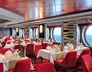 Restaurant chaleureux avec des tables rouges et vue sur la mer, idéal pour des dîners inoubliables | MSC Croisières