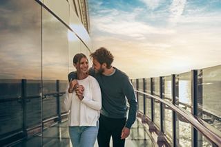 A couple enjoys a moment together on a cruise, looking at a device against a scenic backdrop | MSC Cruises