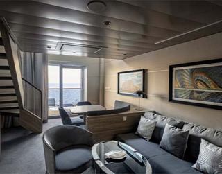 Luxuriöses Kabineninterieur mit komfortablen Möbeln und einem großen Fenster, das den Raum erhellt | MSC Cruises