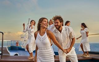 A couple enjoys a romantic moment on the ship's deck, surrounded by friends | MSC Croisières